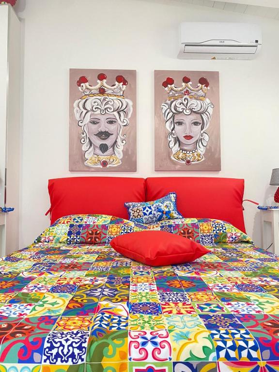 a bedroom with a colorful bed with two paintings on the wall at MARINA BAY in Terrasini