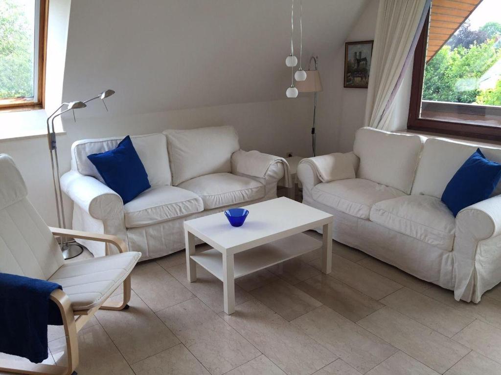 a living room with two white couches and a table at Ferienwohnung-Gottorf in Ulsnis