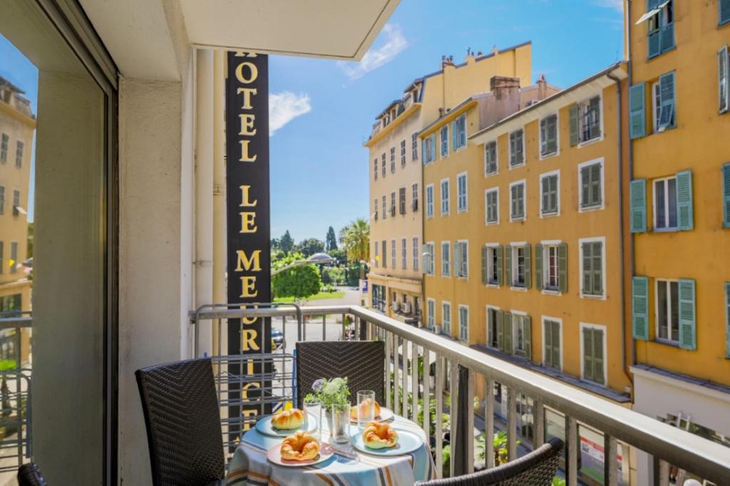 a table on a balcony with a view of a street at SUEDE AP4207 by Riviera Holiday Homes in Nice