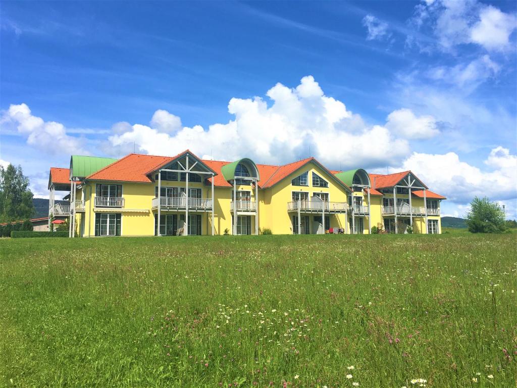 ein großes gelbes Haus mit roten Dächern auf einem Feld in der Unterkunft Lipno - Seepark Residence in Horní Planá