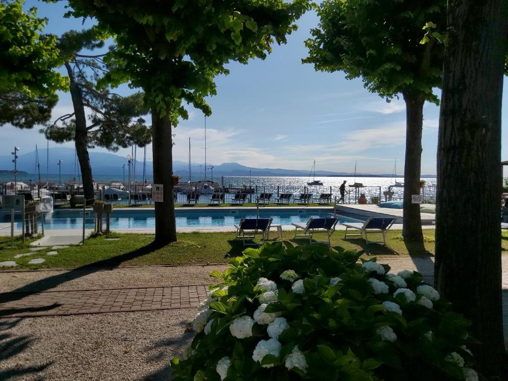 a swimming pool with trees and a body of water at Villaggio Turistico dei Tigli in Padenghe sul Garda