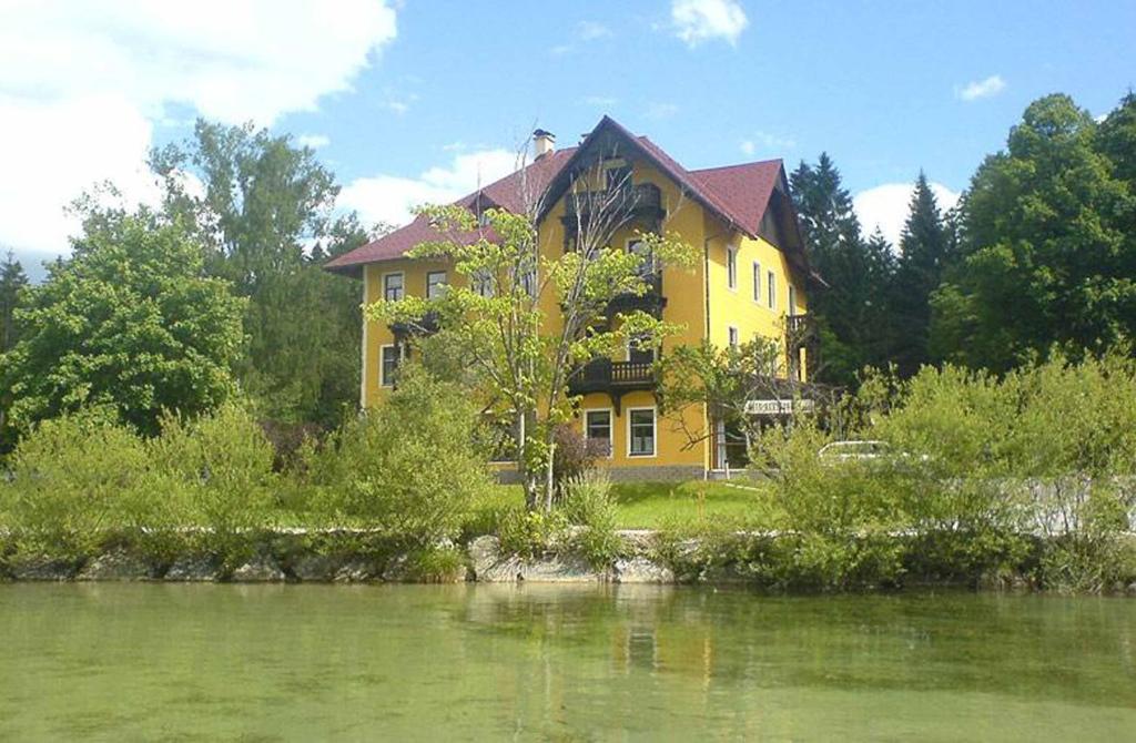 uma casa amarela sentada ao lado de um corpo de água em Ferienwohnung Engleitner - DorfResort Mitterbach em Mitterbach