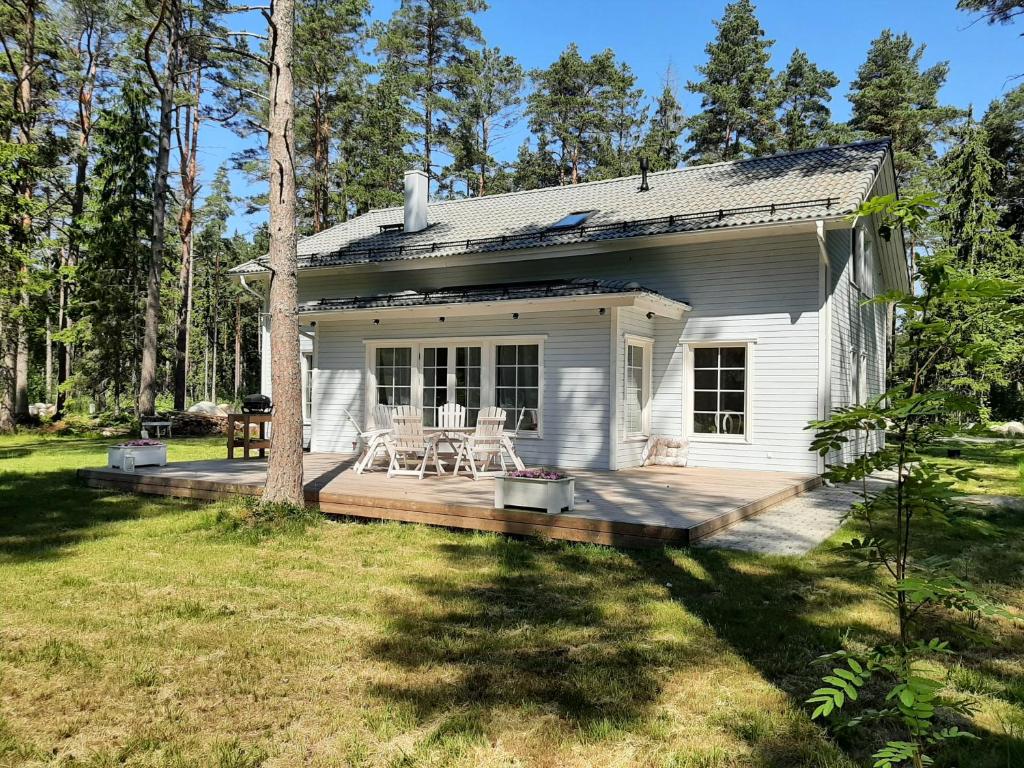 ein weißes, kleines Haus mit einer Veranda und einer Terrasse in der Unterkunft Villa de la Mer holiday home in Kaberneeme