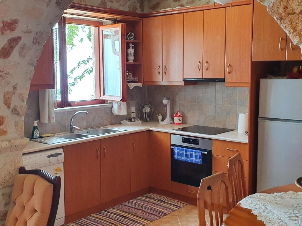 a kitchen with wooden cabinets and a sink and a refrigerator at Nireas : Stone Villa in Zakynthos