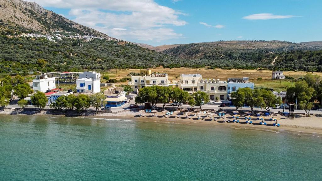 a view of a beach with chairs and buildings at Almiriki Chios Rooms & Apartments in Líthion