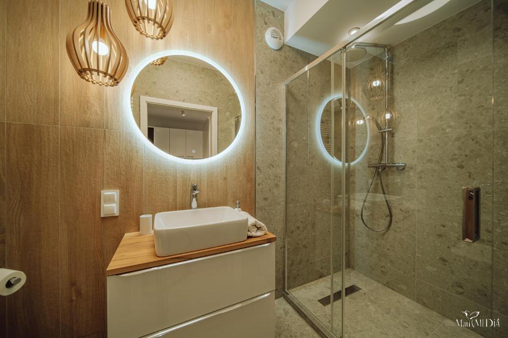 La salle de bains est pourvue d'un lavabo et d'une douche avec un miroir. dans l'établissement Apartament Silence Karpatia Resort z Kominkiem, à Karpacz