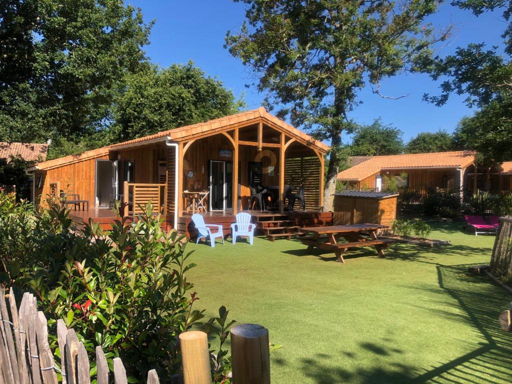 eine kleine Hütte mit einem Rasenhof mit einem Tisch und Stühlen in der Unterkunft Chalet prestige au coeur du Bassin d'Arcachon in La Teste-de-Buch