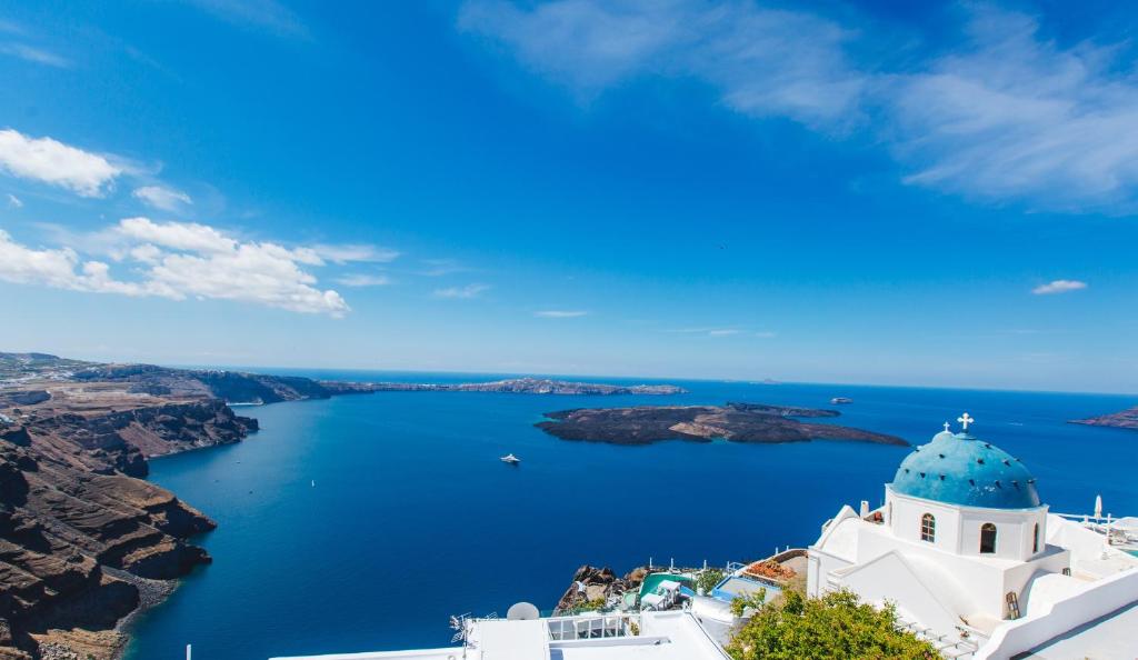 a white building with a blue dome on top of a lake at Blue Moon Villa in Imerovigli