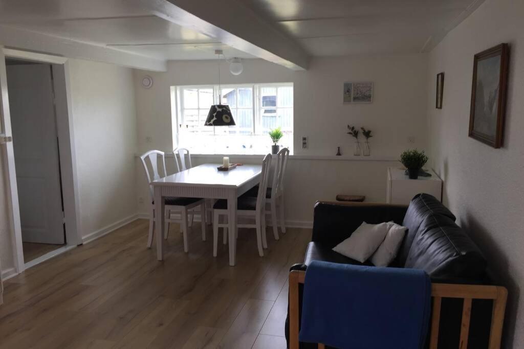 a living room with a couch and a table and chairs at Gammelt Mandø hus Hyggebo in Ribe