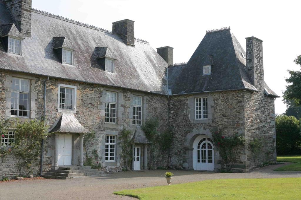 an old stone building with a black roof at Le Logis d'Equilly in Équilly