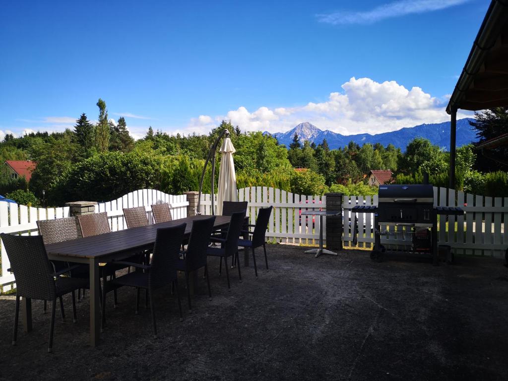 a wooden table and chairs with a fence and mountains at Haus Im Grünen in Villach