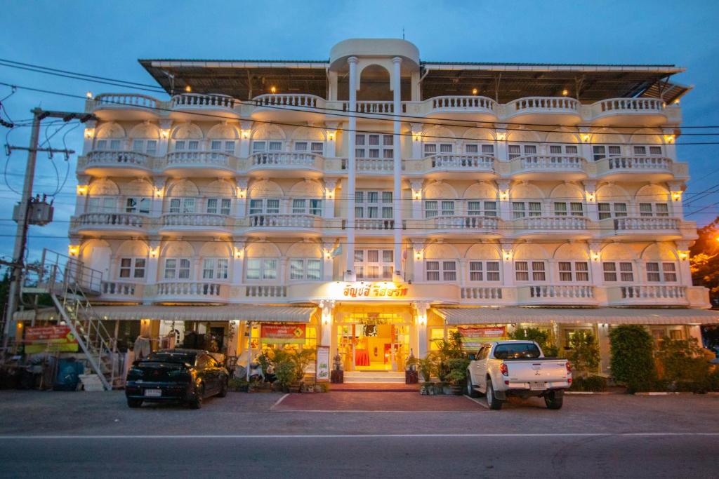 un gran edificio blanco con coches estacionados frente a él en Anchalee Resort en Bang Saphan