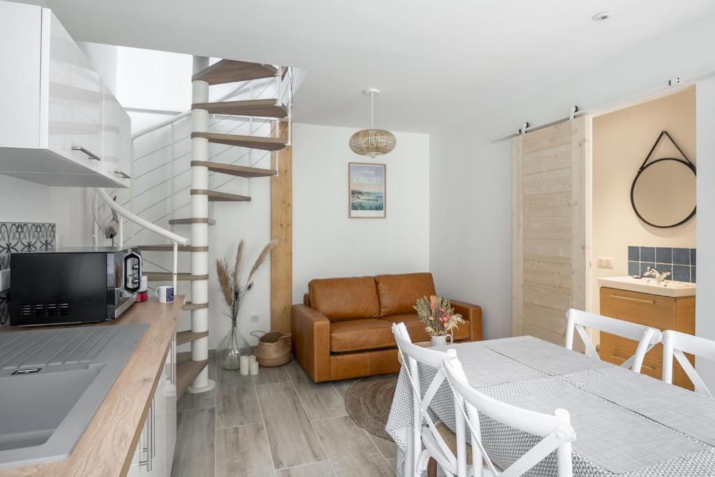 uma cozinha e uma sala de estar com uma mesa e uma escada em espiral em Le Coco - Duplex proche mer em Cancale