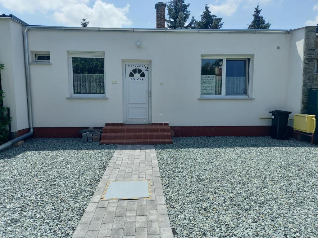 a white house with a door and a gravel driveway at Polgár Vendégház in Bük