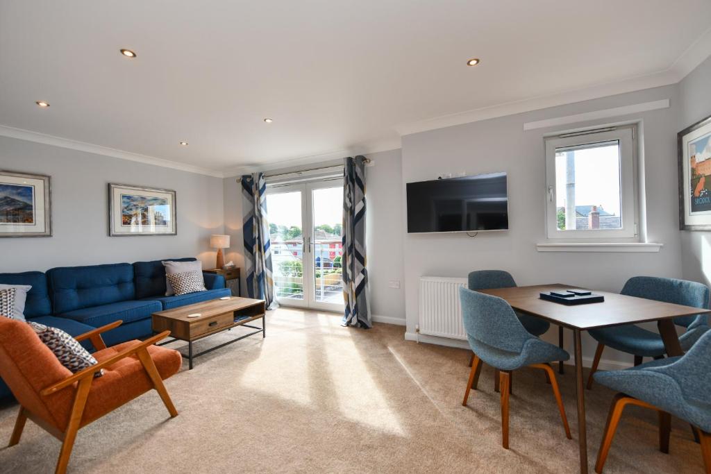 a living room with a blue couch and a table at Troon Executive Apartment in Troon