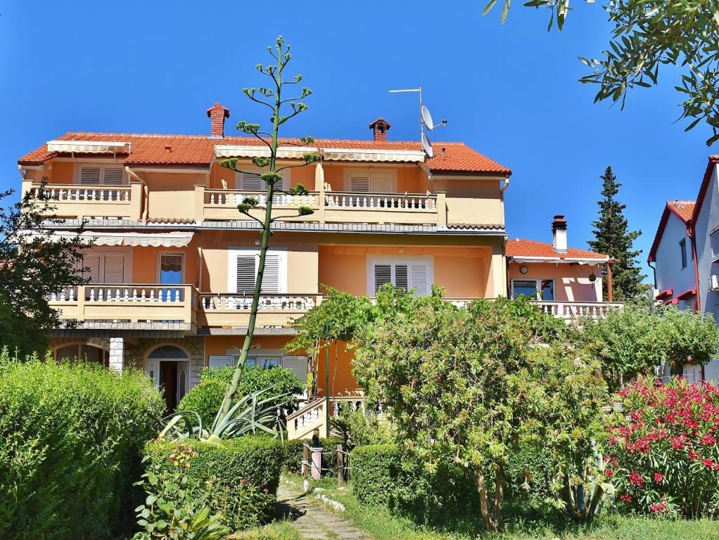 a large orange building with trees and bushes at Guest House Sandra in Rab