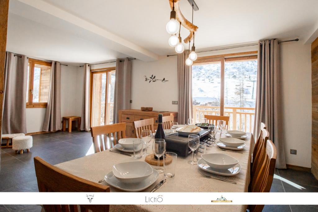 una sala da pranzo con tavolo, sedie e finestra di MARMOTTE 102 - Beau T4 pour 10, aux pieds des pistes a Bonneval-sur-Arc