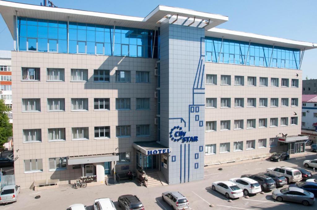 un gran edificio con coches estacionados en un estacionamiento en Hotel City Star, en Perm