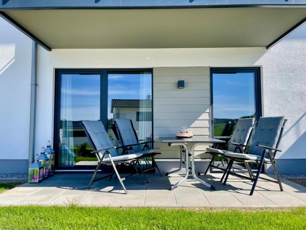 d'une terrasse avec des chaises, une table et des portes en verre. dans l'établissement Sonnenweg 46 - CARLA, à Heringhausen