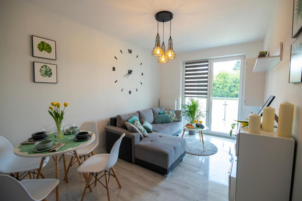 a living room with a couch and a table and a clock at Apartament Laurowa in Tyczyn