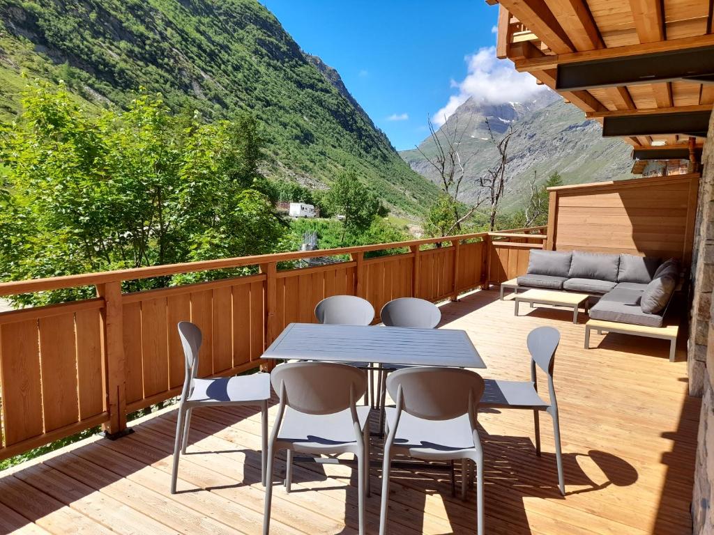 a deck with a table and chairs and a couch at MARMOTTE 003 - Superbe T4 aux pieds des pistes in Bonneval-sur-Arc