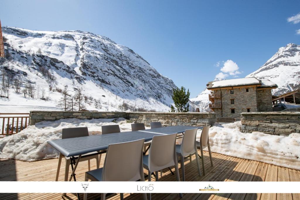 a table and chairs on a deck with snow covered mountains at MARMOTTE 001 - Bel appartement avec grande terrasse, aux pieds des pistes in Bonneval-sur-Arc