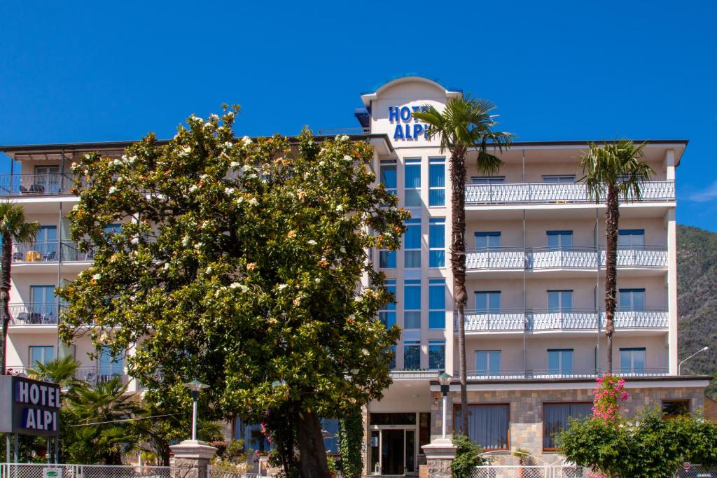 a hotel with palm trees in front of it at Hotel Alpi in Baveno