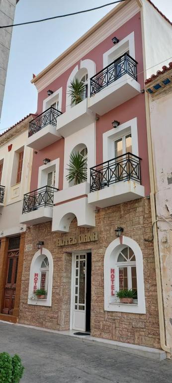 un edificio rosa con balcones en una calle en Hotel Diana en Koroni