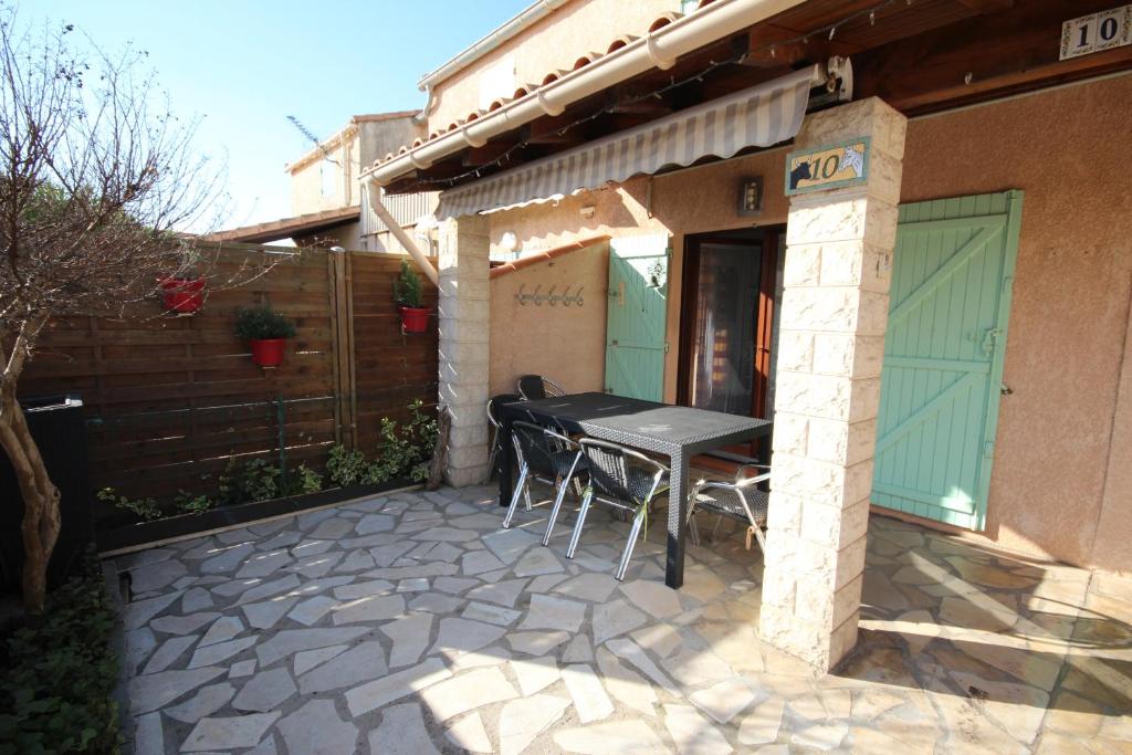 d'une terrasse avec une table et des chaises à l'extérieur d'une maison. dans l'établissement Maison de vacances semi climatisée, 4 pièces 4-5 couchages, seulement 80m de la plage de PORTIRAGNES PLAGE LRCLOS10, à Portiragnes