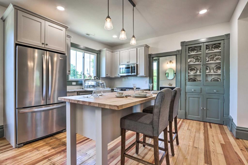 a kitchen with a large island with chairs and a refrigerator at The Ruebling House Cozy Defiance Apartment! in Defiance