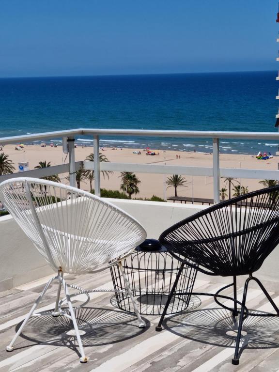 2 sillas sentadas en un balcón con la playa en Ático Zeus, en Gandía