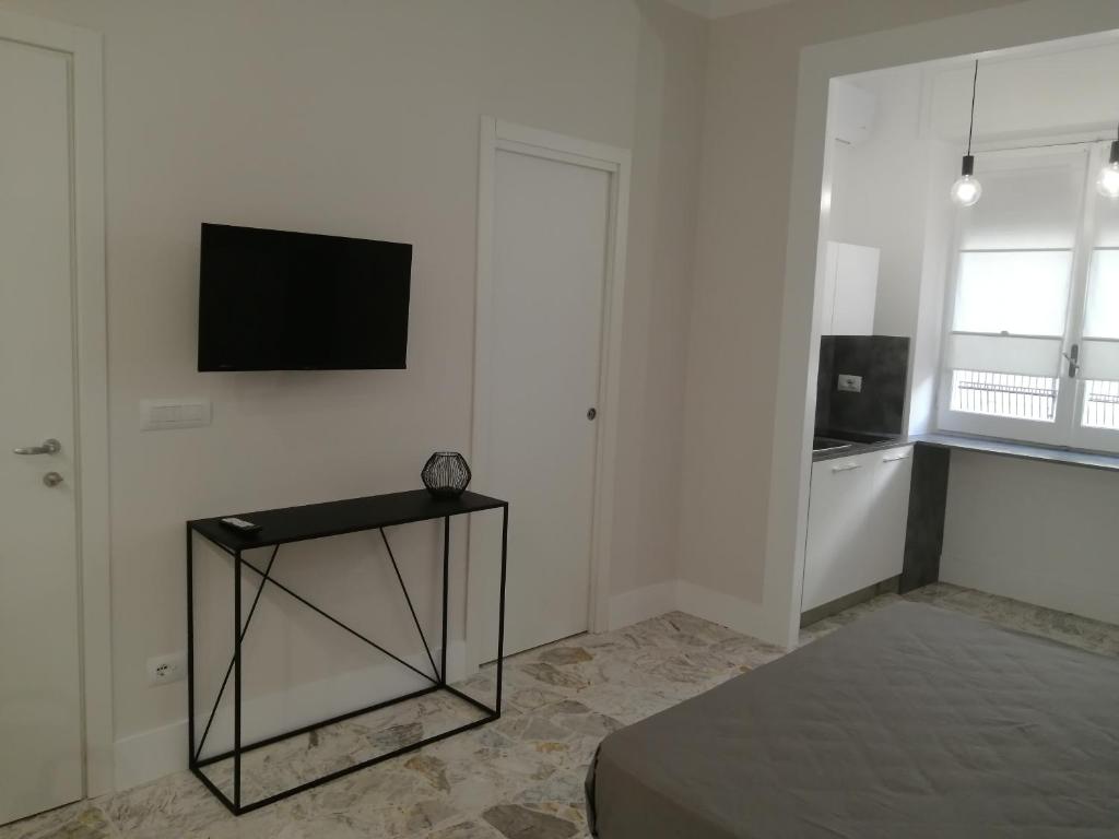 um quarto branco com uma mesa e uma televisão na parede em Insieme al mare em Praia a Mare