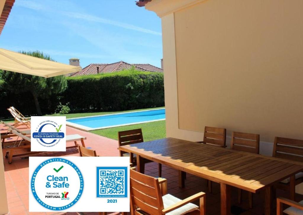 a patio with a table and chairs next to a pool at Dunas Golf House in Cascais