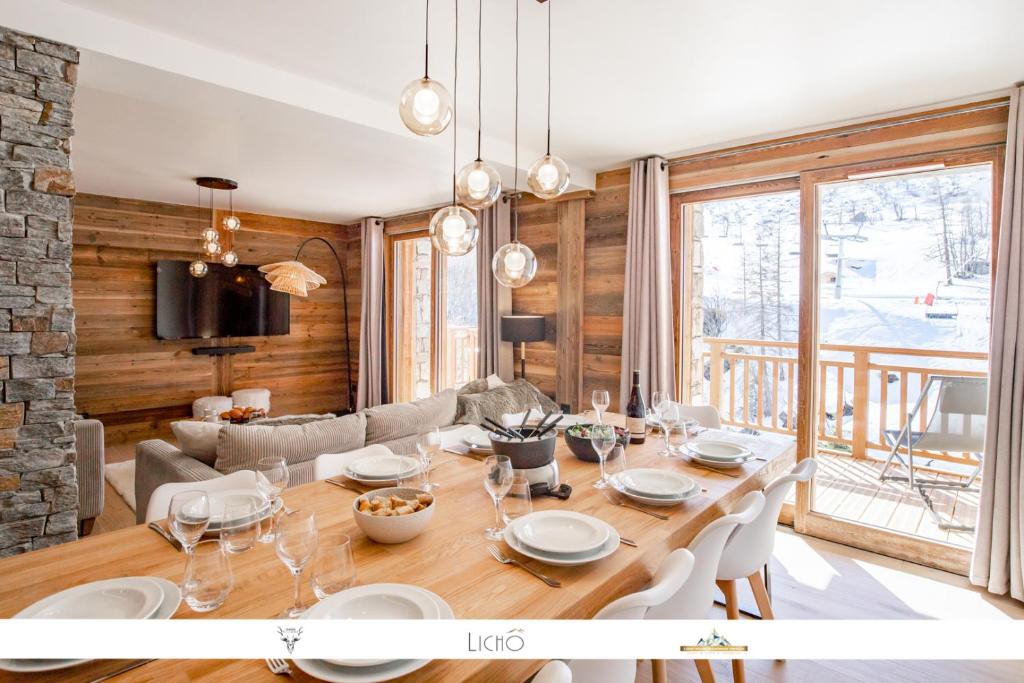 a dining room with a large wooden table with white chairs at Marmotte 103 - Luxueux appartement aux pieds des pistes in Bonneval-sur-Arc