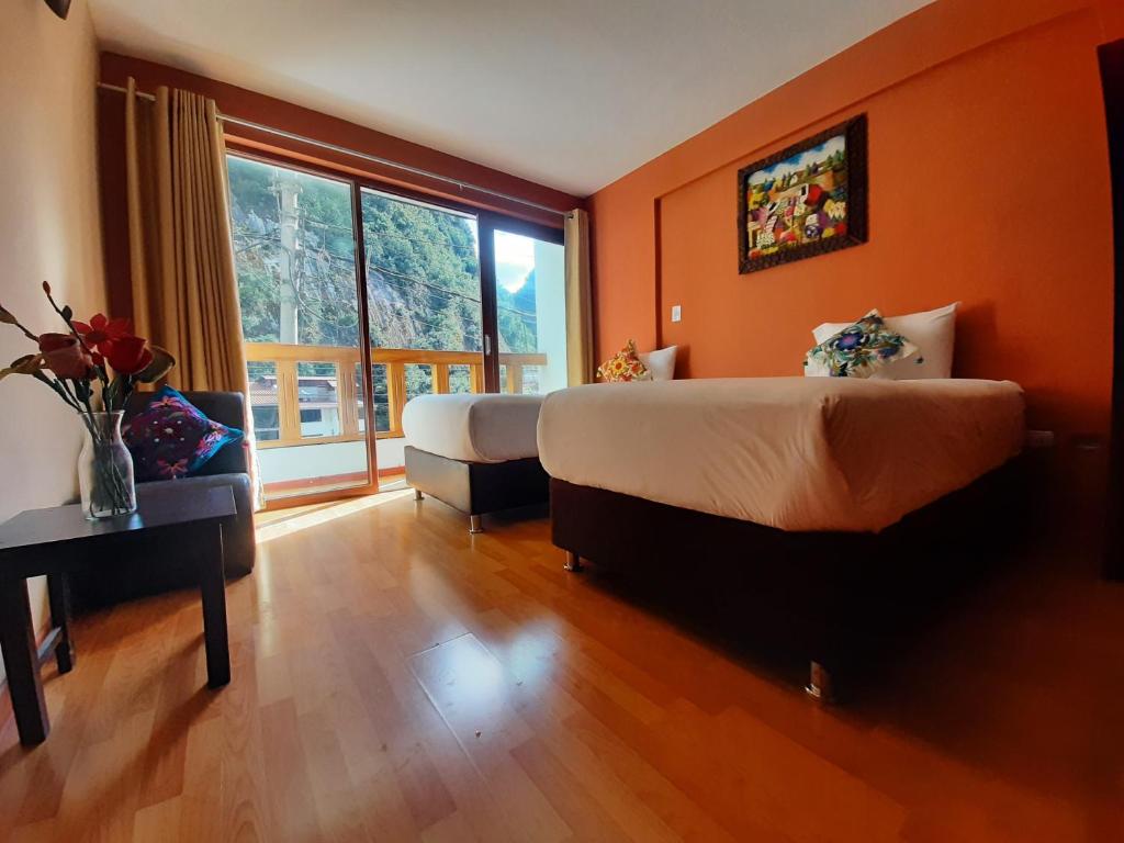 a bedroom with two beds and a large window at USGAR Machupicchu Boutique in Machu Picchu