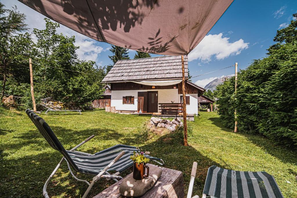 einen Hof mit einem Tisch, einem Stuhl und einem Haus in der Unterkunft Postaja Mir in the heart of Triglav National Park in Bohinj