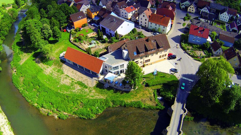 eine Luftansicht eines Hauses auf einer Insel im Wasser in der Unterkunft Landgasthof zum Hirschen in Tauberrettersheim
