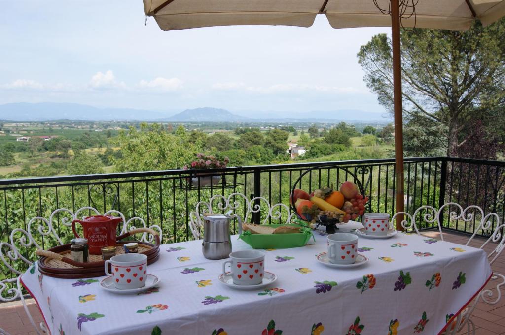 a table with cups and plates of fruit on a balcony at RomaInvilla in Sutri