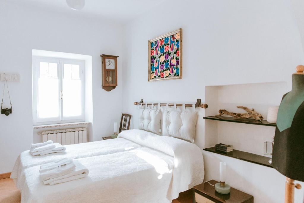 een witte slaapkamer met een groot bed met witte lakens bij VILLA ATRIS in Borghetto di Vara