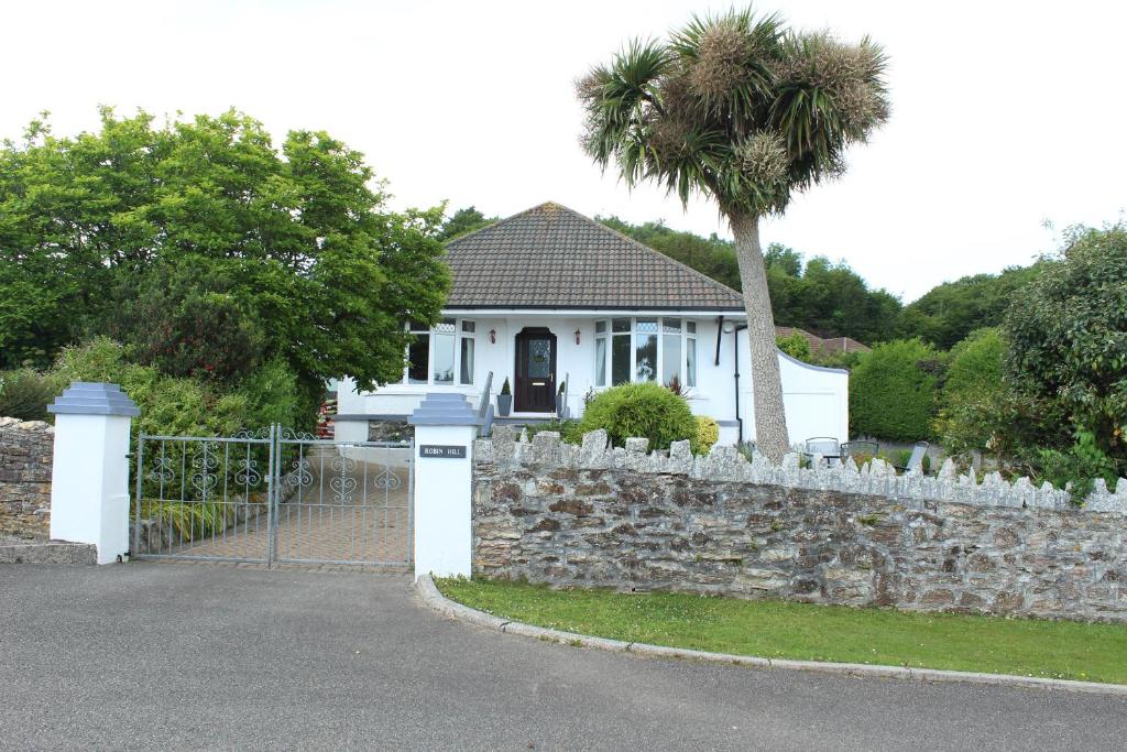 a white house with a fence and a palm tree at Robin Hill in St Austell