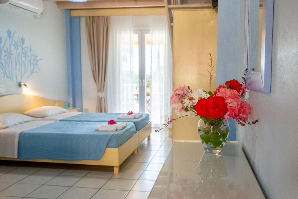 Angelina Apartments في رودا: غرفة نوم مع سرير و مزهرية من الزهور على طاولة