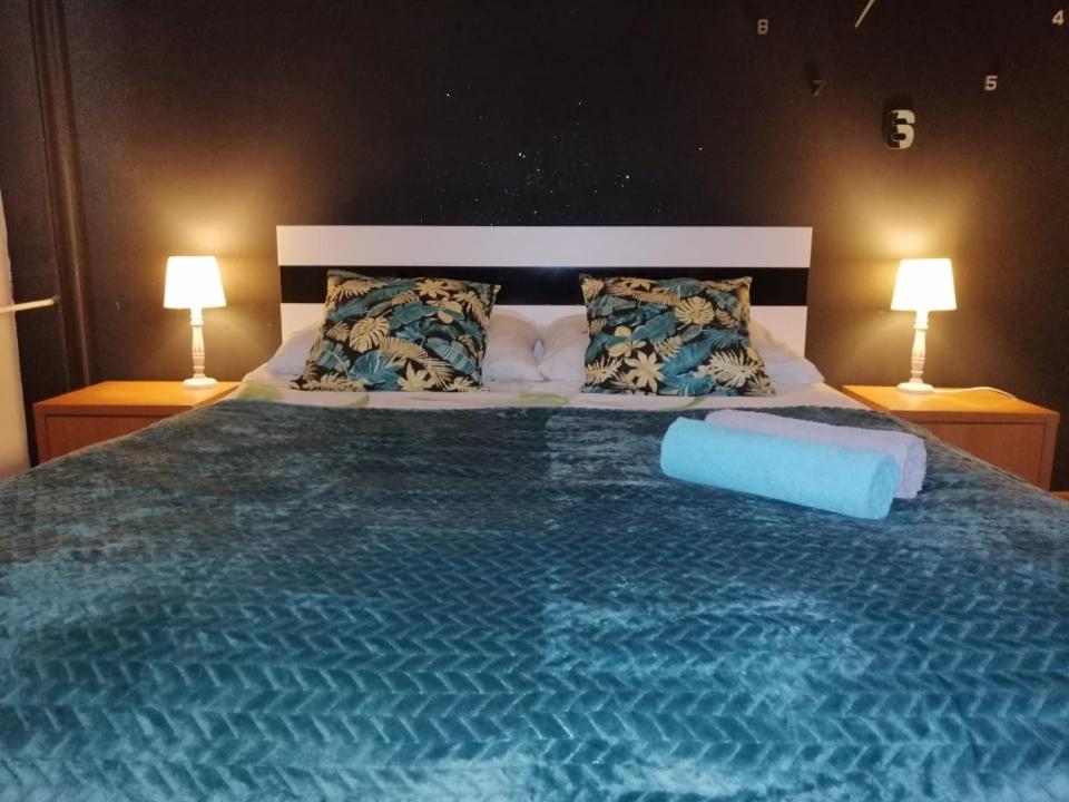 een slaapkamer met een groot blauw bed met 2 lampen bij Apartament M-3 in Częstochowa