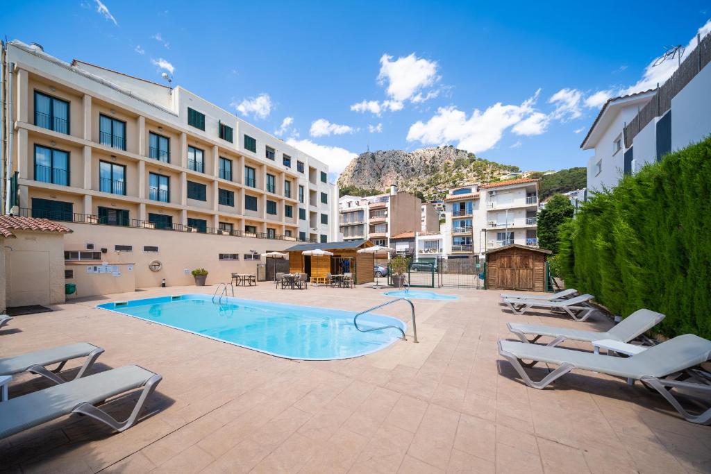 une piscine avec des chaises longues et un hôtel dans l'établissement Hotel Medes II, à L'Estartit