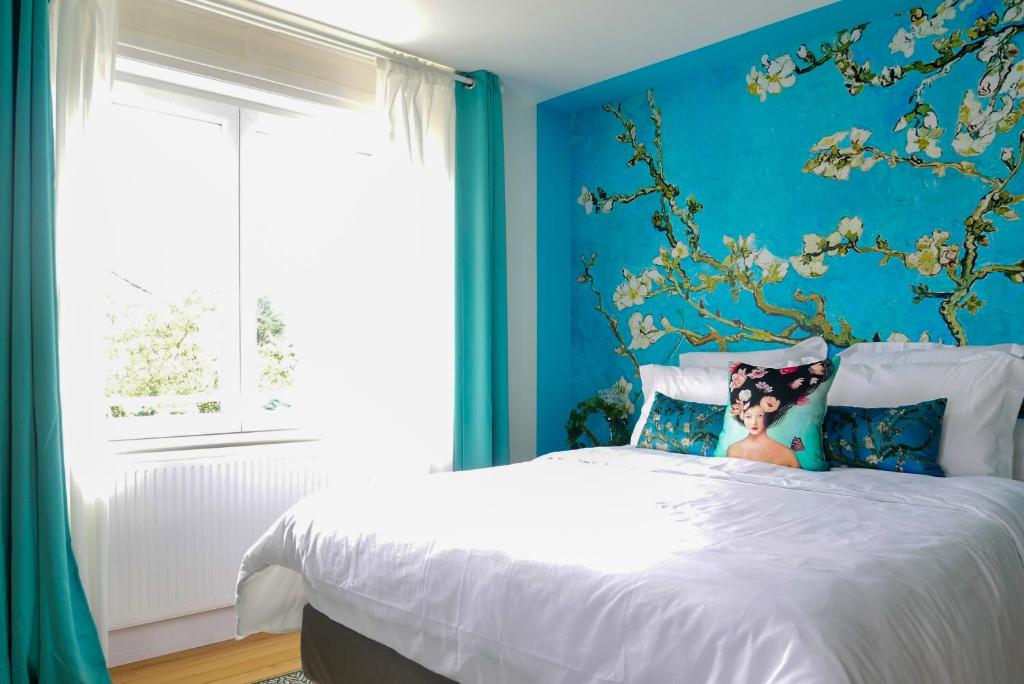 a bedroom with a bed with a blue wall at Maison 1934 - Colmar Gare & Parking gratuit in Colmar