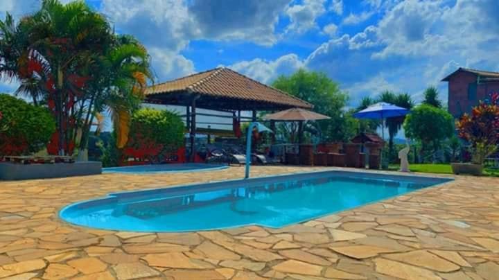 - une piscine dans une cour avec un parasol dans l'établissement Pousada Só Alegria, à Mário Campos