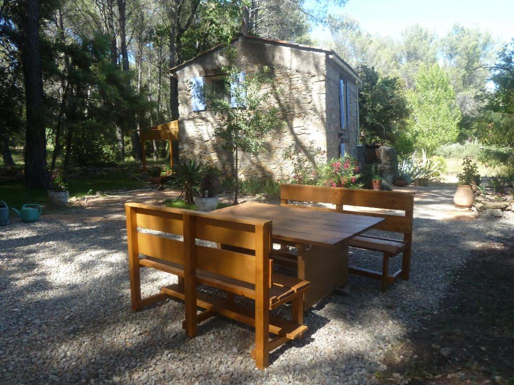 uma mesa de madeira e dois bancos em frente a um barracão em Villa Les Oliviers em Draguignan