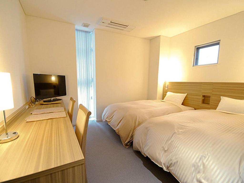 ein Hotelzimmer mit 2 Betten und einem Schreibtisch mit einem TV in der Unterkunft Pure Hotel - Vacation STAY 44185v in Yabu