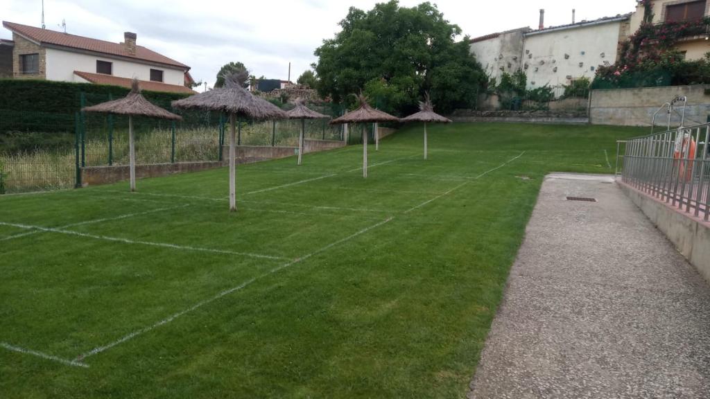 una pista de tenis con sombrillas en un campo de césped en Mercedes Etxea, en Cripán
