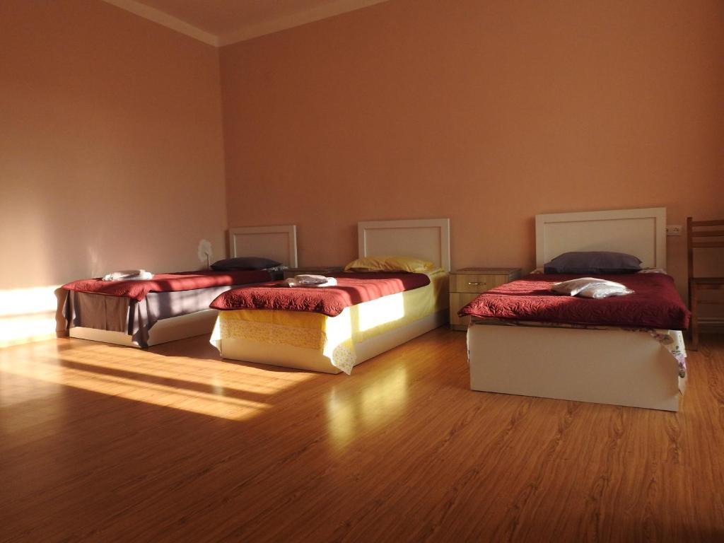 two beds sitting in a room with wooden floors at GoriHouse in Gori