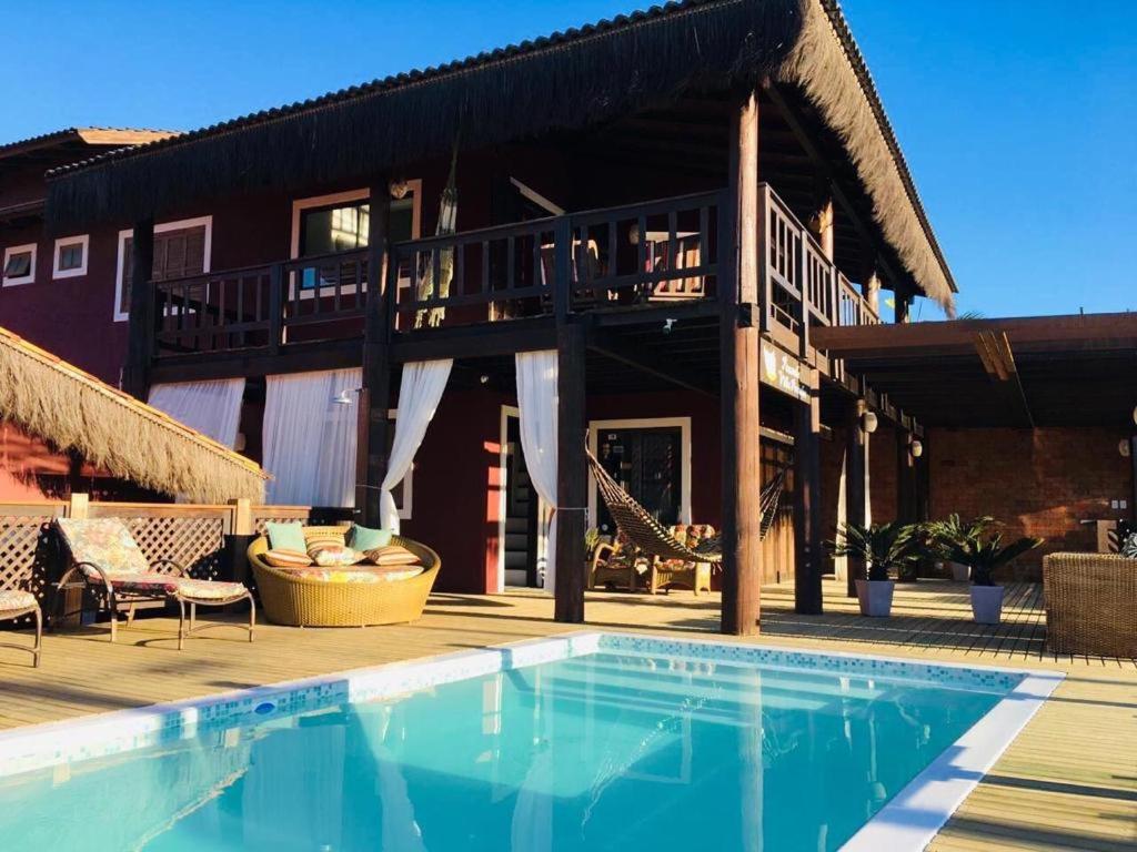 a house with a swimming pool in front of a building at Pousada Villa Prainha in Farol de Santa Marta